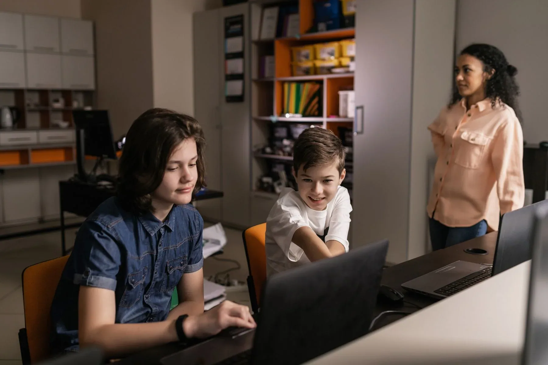 Illustrative classroom scene with students and a teacher using laptops